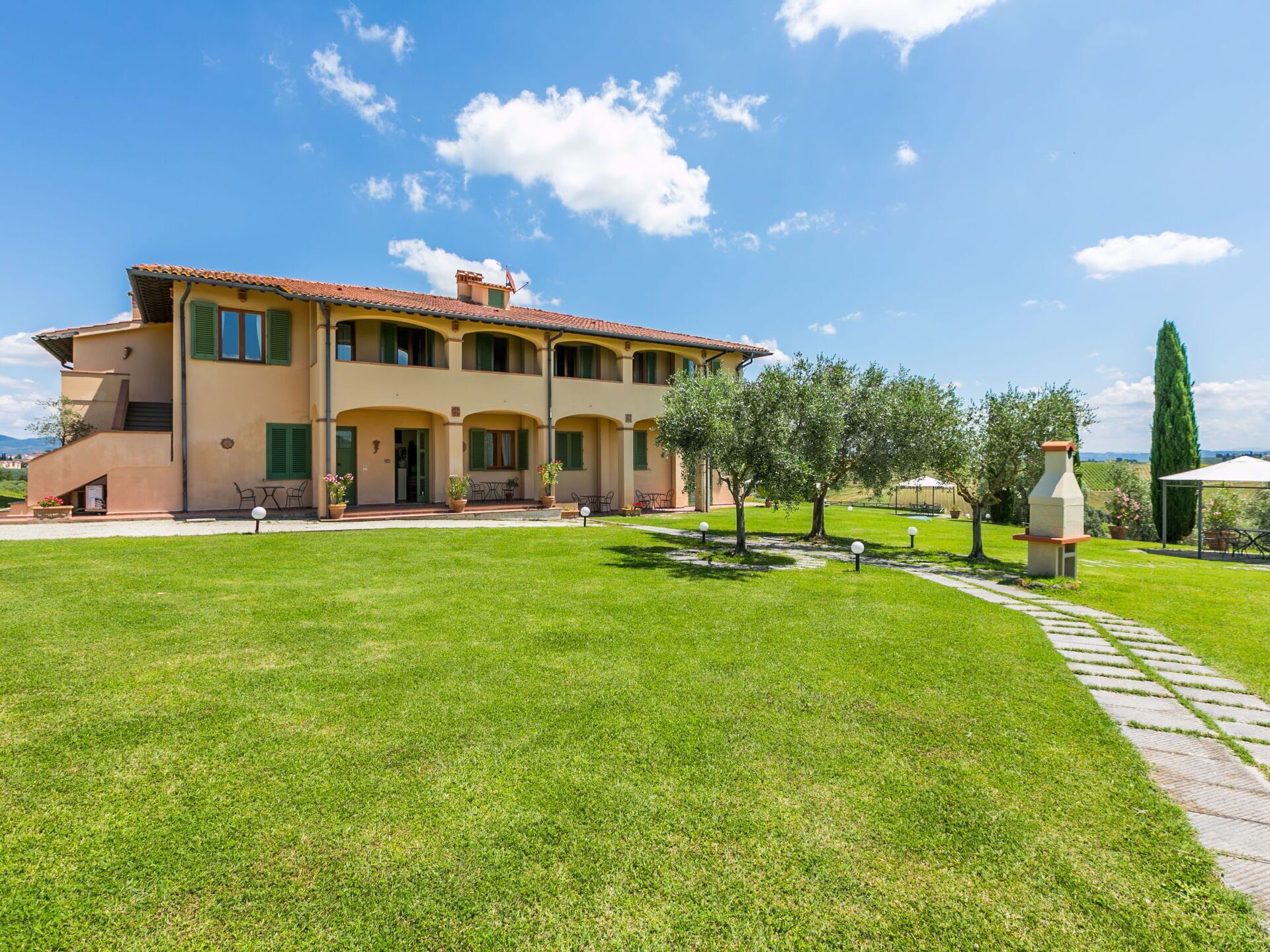 A two-story building with a tiled roof, a paved driveway, and a well-maintained lawn.