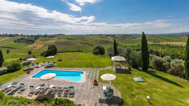 A pool area with lounge chairs and umbrellas, surrounded by a lush garden and vineyards in the background. - Nice apartment for 2 guests with WIFI, A/C, pool, TV and pets allowed (Cerreto Guidi)
