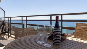 Ein Balkon mit Tisch, zwei Weingläsern und einer Weinflasche.