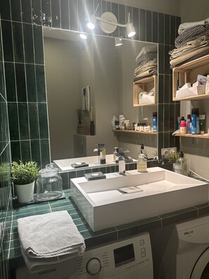 Bathroom features a large sink, mirror, and washing machine.