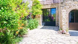 A stone pathway leading to a building with a glass door and a stone wall. - Cosy apartment for 3 guests with WIFI and TV (Six-fours-les-plages)