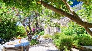 A garden patio with a table and chairs, surrounded by lush greenery and a stone wall. - Cosy apartment for 3 guests with WIFI and TV (Six-fours-les-plages)