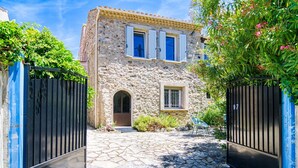 A stone building with a central arched doorway, a small window, and a door with a metal gate. - Cosy apartment for 3 guests with WIFI and TV (Six-fours-les-plages)
