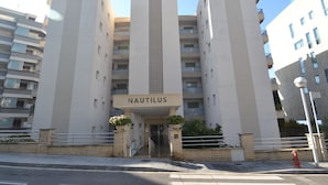 Un bâtiment moderne dont l’entrée est marquée par une grande inscription « NAUTILUS ». Il se distingue par un élément vertical central et de nombreux balcons.