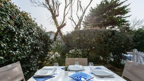 An outdoor dining area with a table set for four, surrounded by greenery and trees.