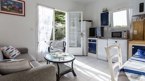 A compact living space with a kitchenette, a dining area, and a seating area with a glass table.
