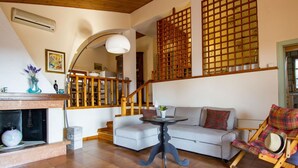 Una sala de estar acogedora con chimenea, un sofá, una mesa de comedor y una silla de madera.