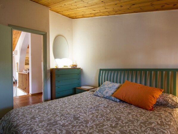 A bedroom with a bed, a dresser, a mirror, and a wooden ceiling.