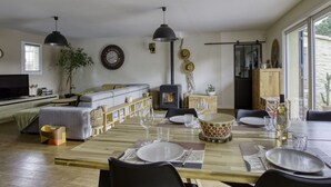 Un salon moderne comprenant un canapé, un téléviseur et un coin repas avec une table et des chaises en bois.