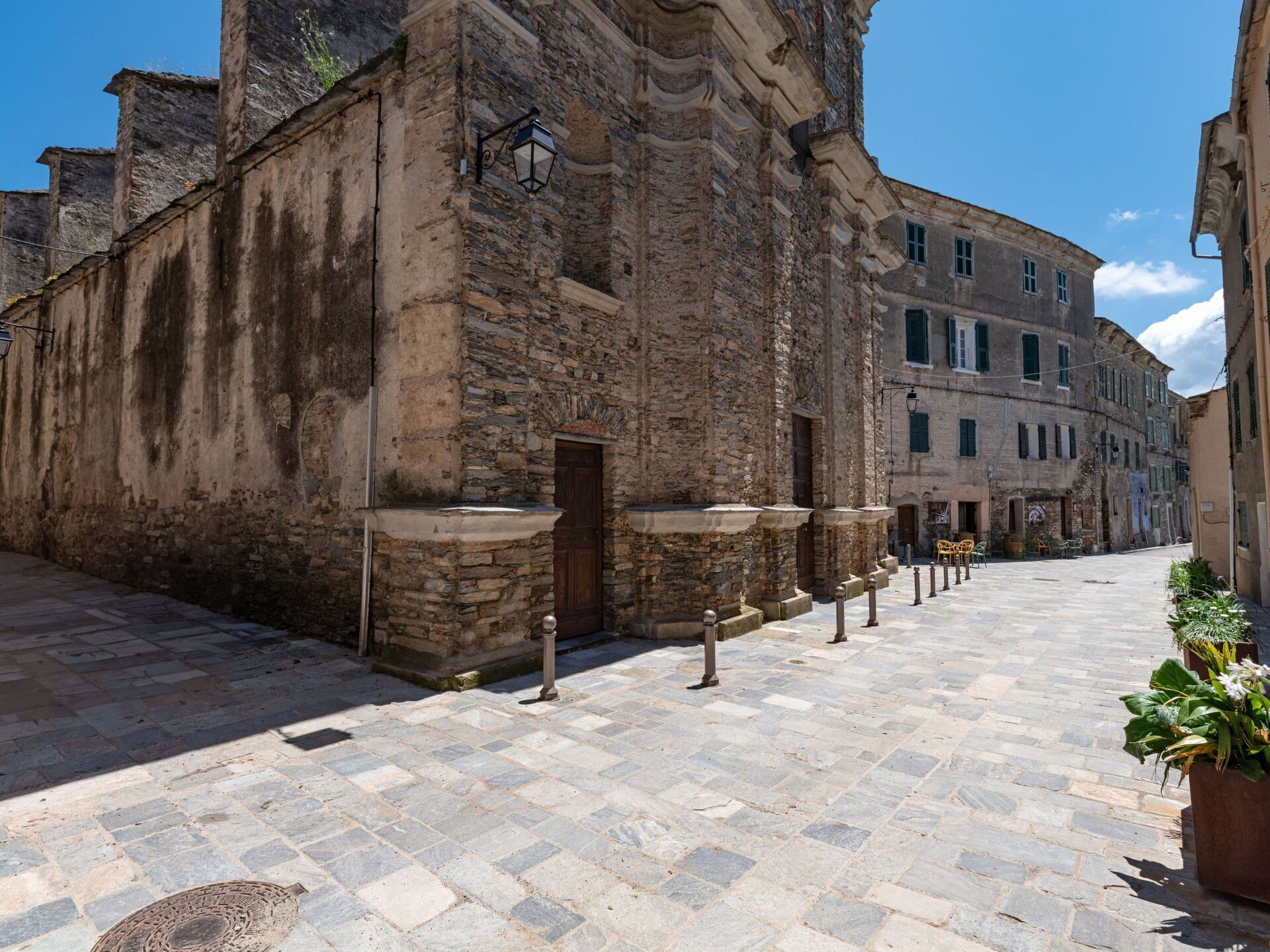 Edifici de pedra amb una porta de fusta, una escala de pedra i un carrer pavimentat.