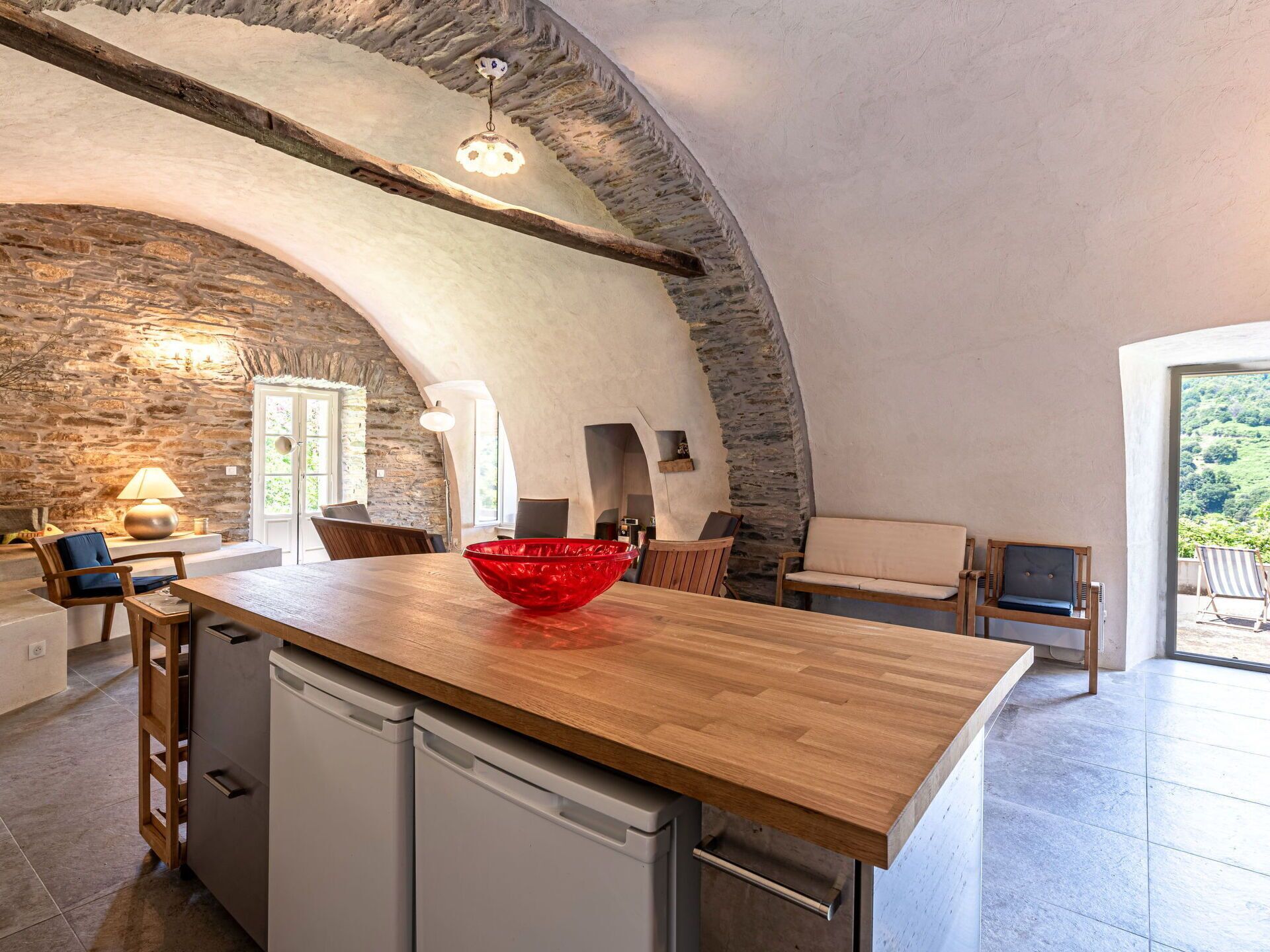 A kitchen with a wooden island, stone walls, and a view of the outdoors.