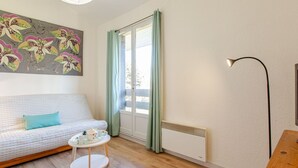 Ett mysigt vardagsrum med en soffa, ett litet runt bord, ett element och en golvlampa.
