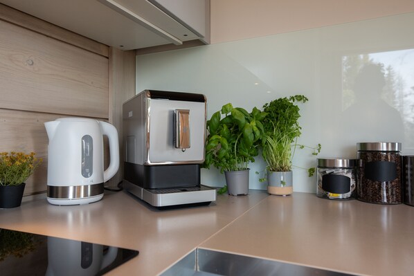 Eine moderne Küche mit Kaffeemaschine, Wasserkocher, Topfpflanzen und Kaffeebehältern.