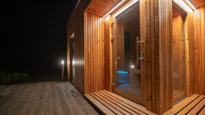 Een houten hut met een glazen deur en een houten terras.