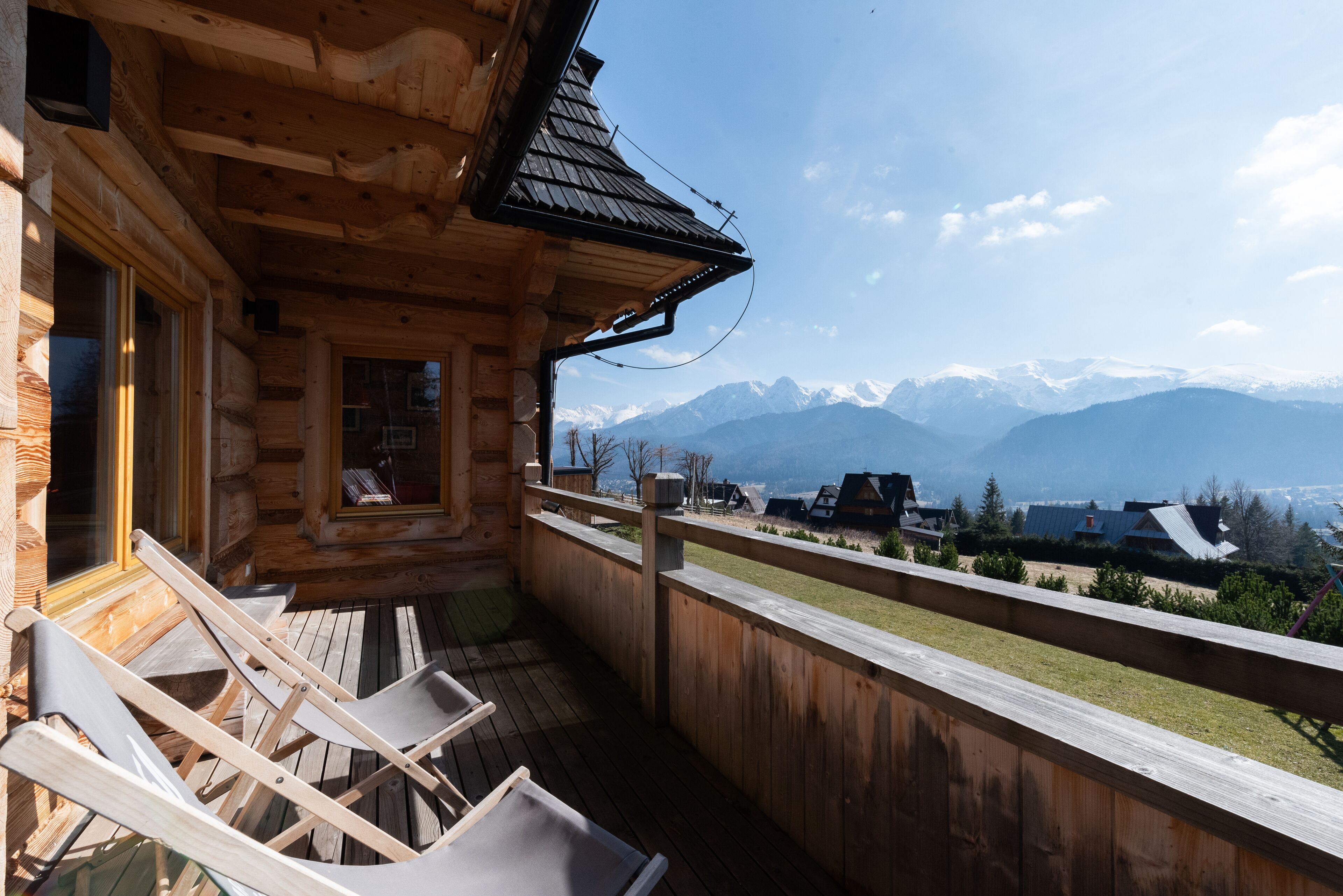 A wooden cabin with a balcony overlooking a mountainous landscape.