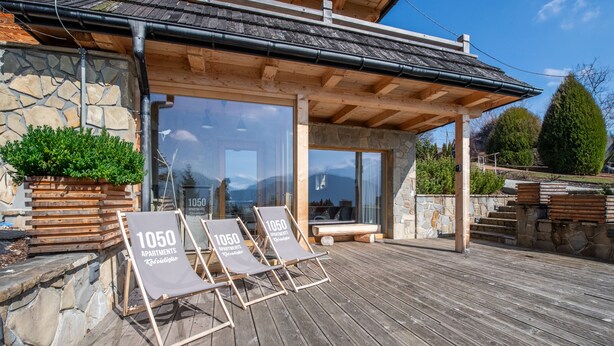 Een houten terras met lounge stoelen en een stenen muur.
