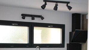 Een moderne keuken met houten kastjes, een zwart aanrecht, een dubbele spoelbak en een raam boven de spoelbak.