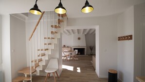 Een modern interieur met een houten trap, witte muren en een eethoek met natuurlijk licht.