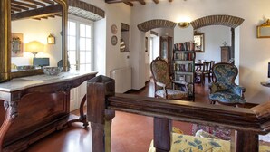 Une chambre de style traditionnel avec des poutres apparentes, un grand miroir décoratif, un bureau en bois et un fauteuil classique.