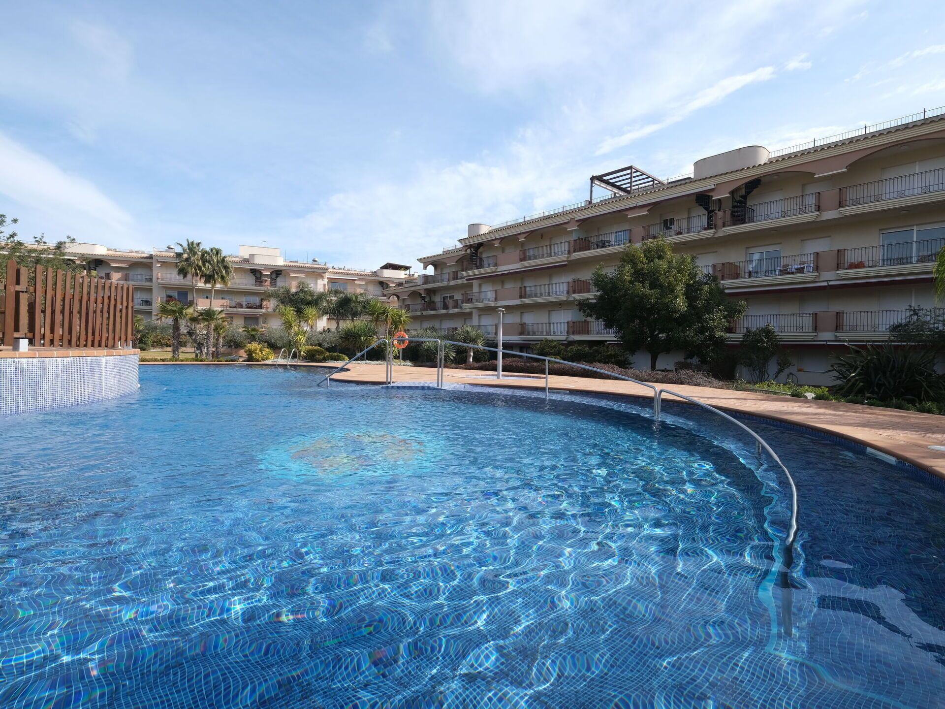 Ein Swimmingpool mit glasklar blauem Wasser, umgeben von einem Poolbereich mit Fliesenboden und Holzzaun.