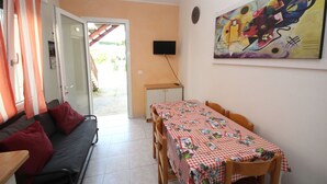 Ein gemütliches Wohnzimmer mit einer Couch, einem Esstisch mit kariertem Tischlauf und einem Bild an der Wand.