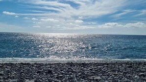Een rotsachtig strand met de oceaan en een heldere lucht.