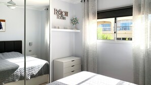 Een slaapkamer met twee bedden, een garderobe, een plank met decoratieve objecten en een raam met uitzicht op een gebouw.