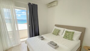 Ett hotellrum med en säng, utsikt över havet och en balkong med gardiner.