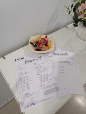 A menu with a 'Bienvenue!' greeting, a small bowl of assorted candies, and a white table with a floral arrangement. - Ideal for business travelers and vacationers. (Santa Eufemia Lamezia)