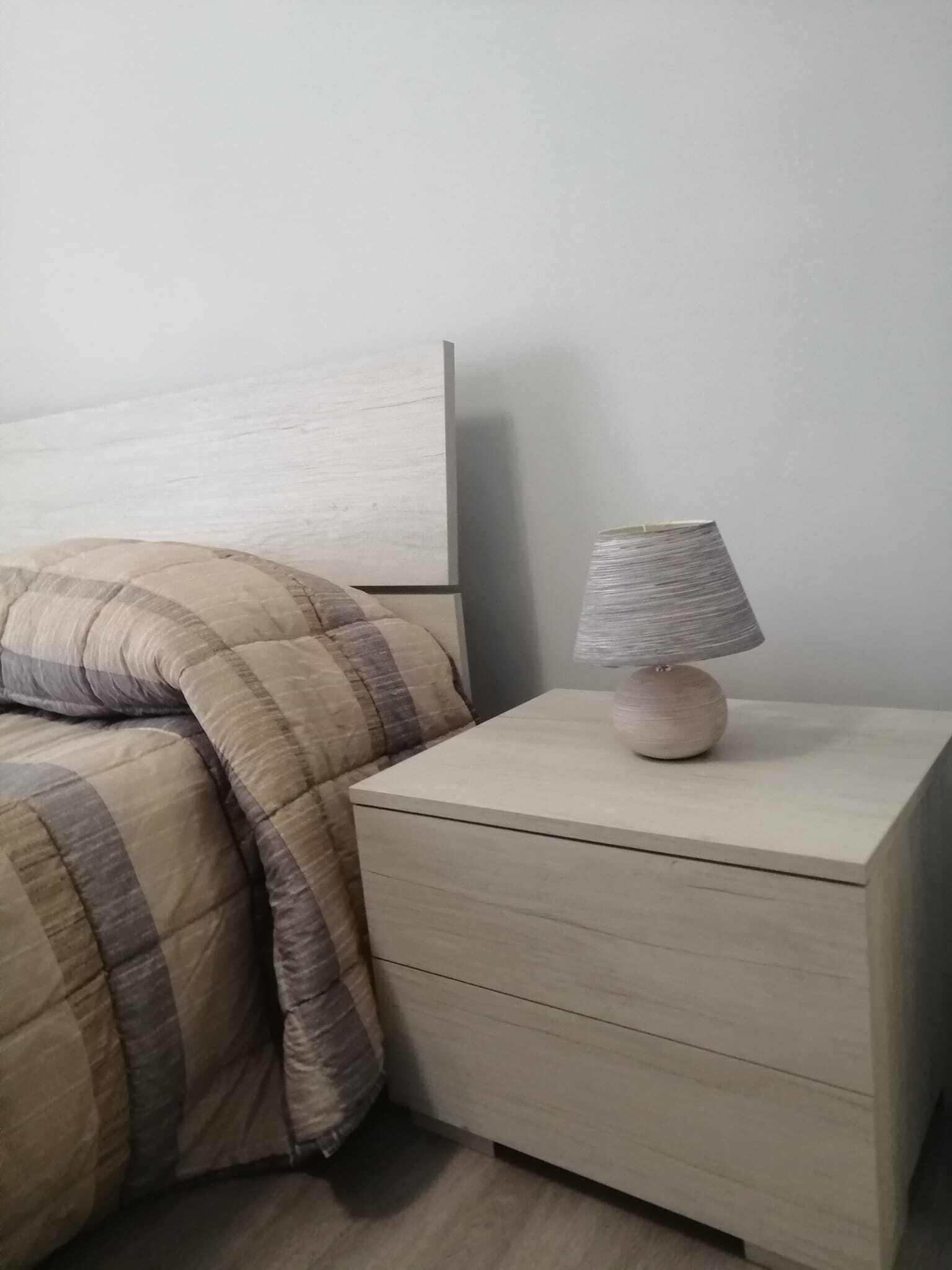 Un lit avec une couverture à rayures et une table de chevet avec une lampe.