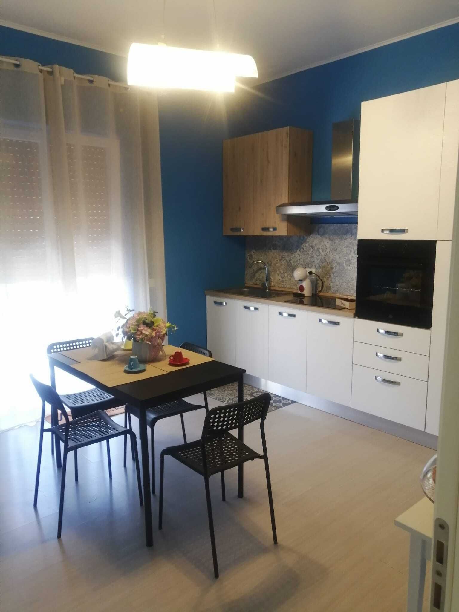 A modern kitchen with white cabinets, a black countertop, and a stainless steel range hood.
