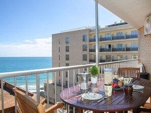 Enjoy ocean views from this balcony with a dining table, chairs, and a potted plant.