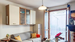 Ein kleiner Wohnraum mit einer Couch, einem Esstisch und einem Kühlschrank.