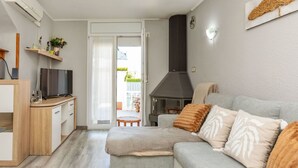 Een moderne woonkamer met een bank, een televisie, een haard en een keuken.