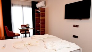 A hotel room with a bed, a TV mounted on the wall, a desk with a chair, and a window with curtains. - Renk Otel Karşıyaka (Izmir)