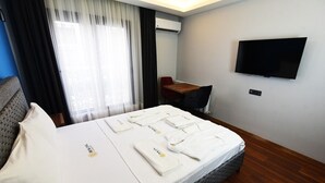 A hotel room with a bed, a desk, a chair, a TV, and a window with curtains. - Renk Otel Karşıyaka (Izmir)