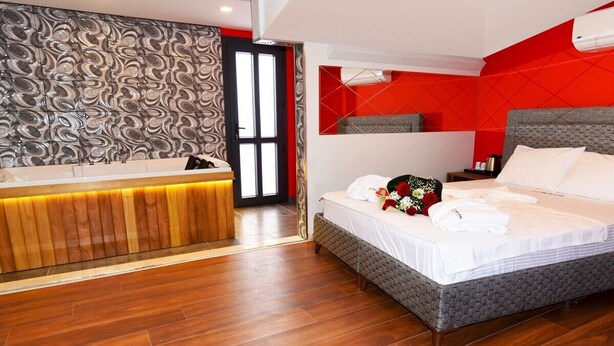 A hotel room with a wooden reception desk, a bed with white linens, and a red accent wall. - Renk Otel Karşıyaka (Izmir)