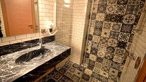 A bathroom with a black marble sink, a mirror, and a shower with patterned tiles. - Renk Otel Karşıyaka (Izmir)