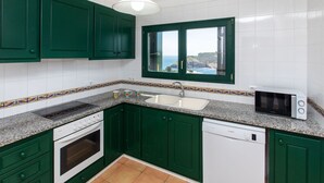 A kitchen with green cabinets, white tiles, a built-in oven, a dishwasher, and a microwave. - Wonderful private villa for 6 guests with pool, TV, terrace and panoramic view (L'escala)