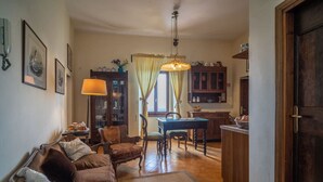 A cozy living room with a sofa, chairs, a dining table, and a kitchen area in the background. - Appartamento la Terrazza (Montasola)