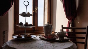 A table with a floral tablecloth, a tiered tray with pastries, a teapot, and a cup on a tray. - Appartamento la Terrazza (Montasola)