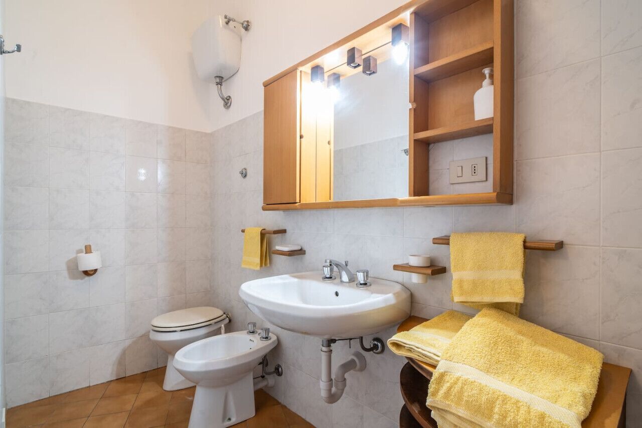Een badkamer met een wastafel, toilet, bidet en een spiegel boven de wastafel.