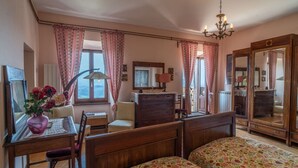 A bedroom with a wooden bed, a desk with a vase of flowers, a chair, a dresser, and a large mirror. - Appartamento la Terrazza (Montasola)