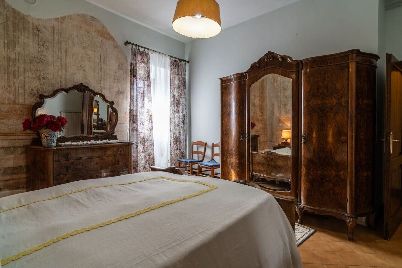 A bedroom with a large bed, wooden dresser, and a mirror.