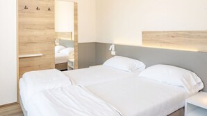 Een moderne hotelkamer met een groot bed, een houten garderobe en een nachtkastje.