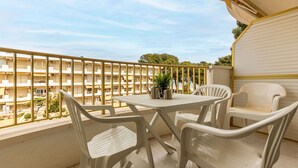 Un balcon doté d’une table et de chaises, donnant sur un immeuble qui possède de nombreux balcons.