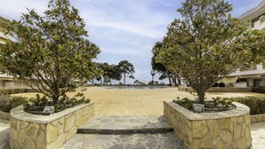 Une cour avec une piscine, entourée de jardinières en pierre et d’arbres.