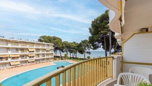Un balcon d’hôtel avec piscine, donnant sur une plage et un immeuble doté de nombreux balcons.
