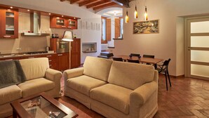 A spacious living area with a wooden ceiling, a sofa, a coffee table, and a dining table with chairs.