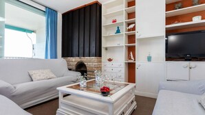 Ein modernes Wohnzimmer mit Kamin, weißen Sofas, einem Couchtisch mit Dekoration und einem Fernseher.